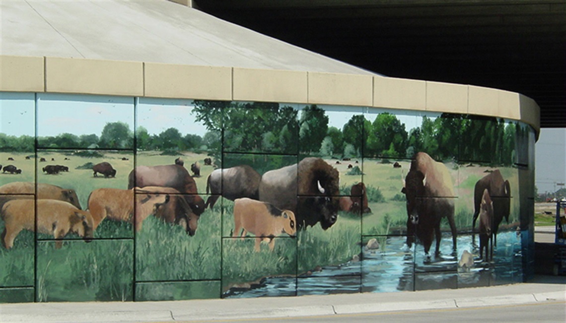 Mural on the wall at the intersection of I-30 and Belt Line Road. The mural depicts a prairie scene with buffalo drinking water and grazing.
